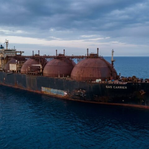 Grand méthanier russe avec des réservoirs sphériques rouillés flottant sur une mer calme sous un ciel gris nuageux.